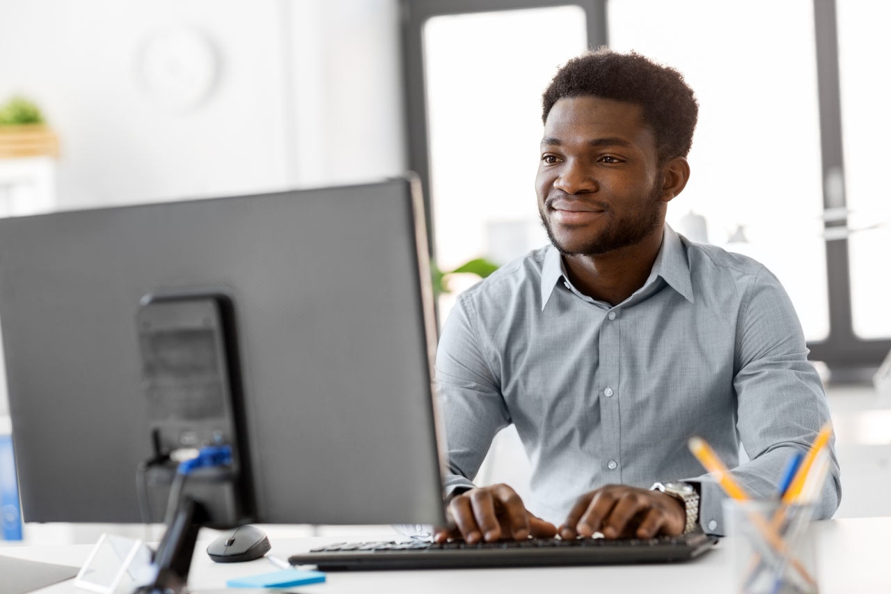 business, people and technology concept - african american businessman with computer working at office