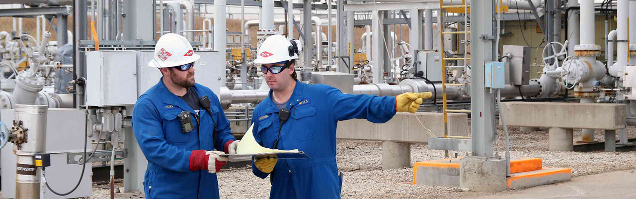 Two Dow employees in a plant discuss work plans